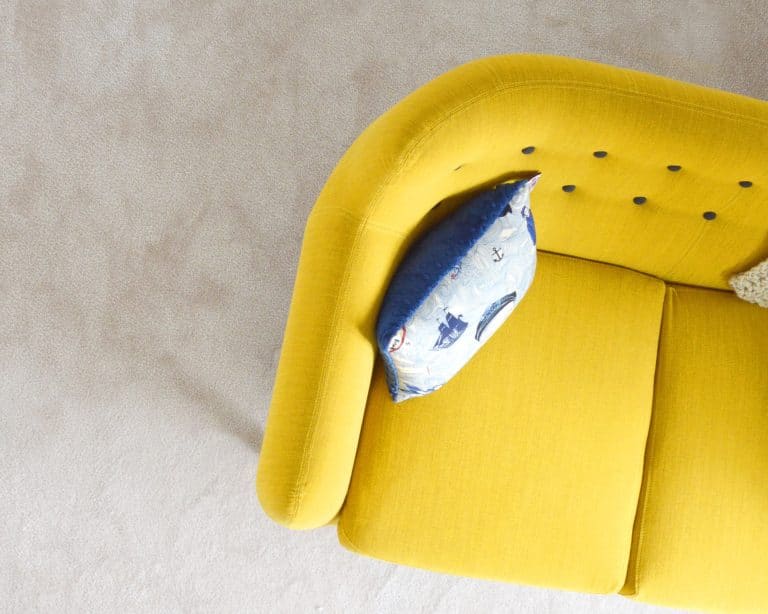 yellow sofa sitting on cream carpet